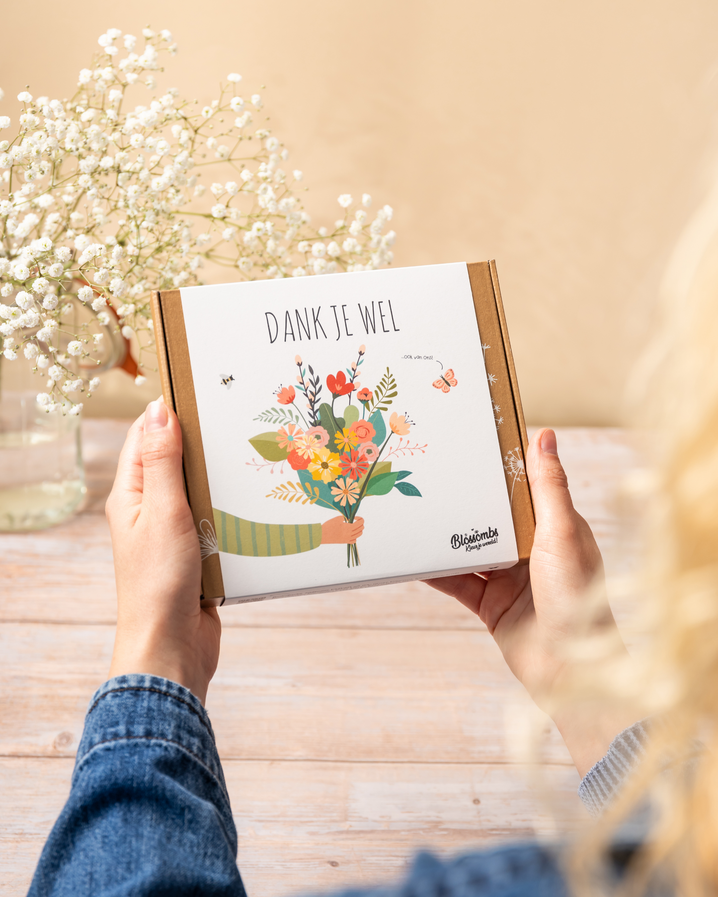 geschenkdoos 'dank je wel' in handen met tafel op achtergrond